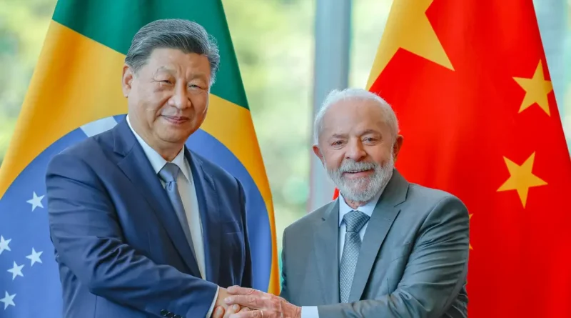 Lula e outro homem de terno apertam as mãos diante das bandeiras do Brasil e da China após anúncio de isenção de visto.